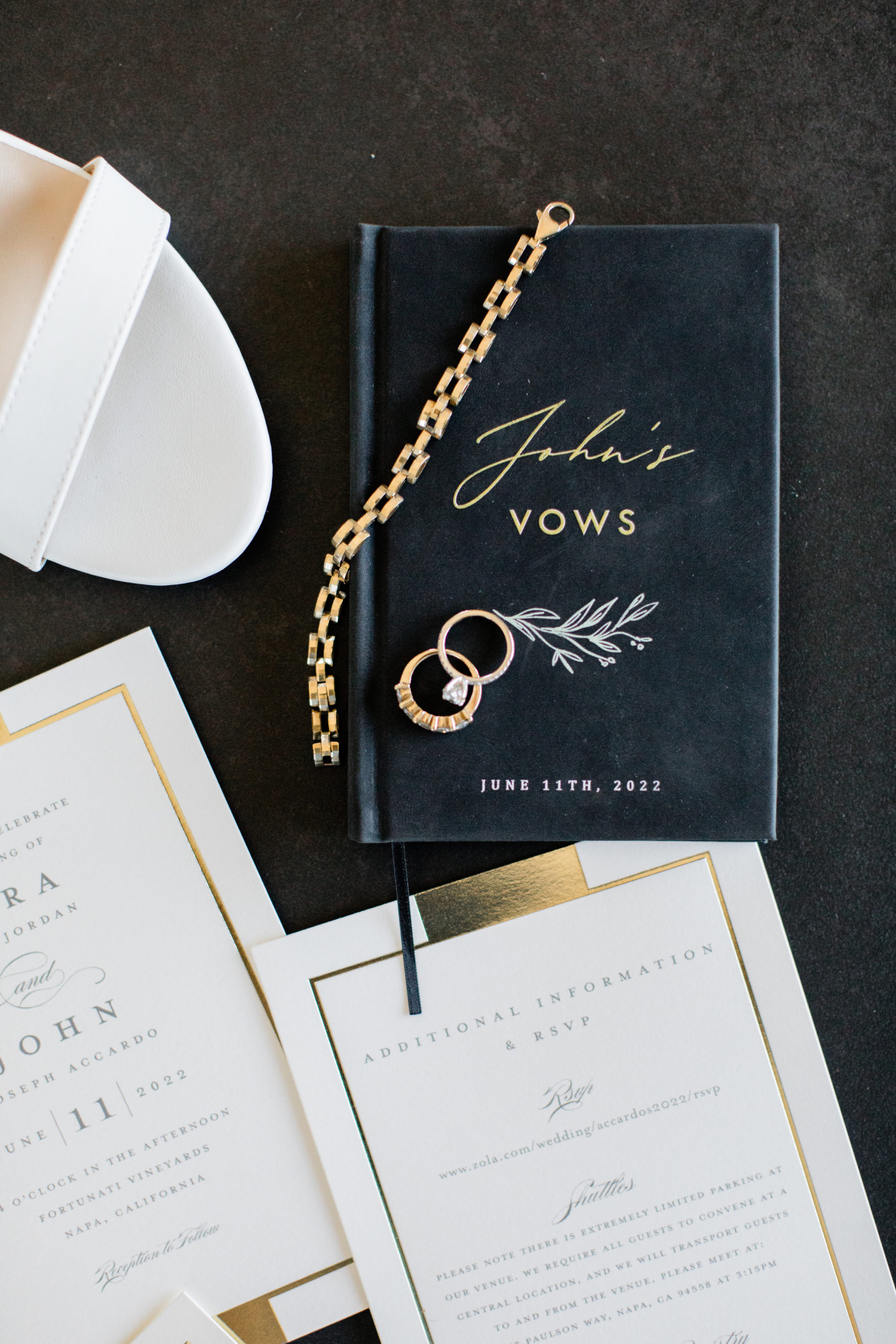 A gold bracelet and two gold rings on top of a "John's vows" book.
