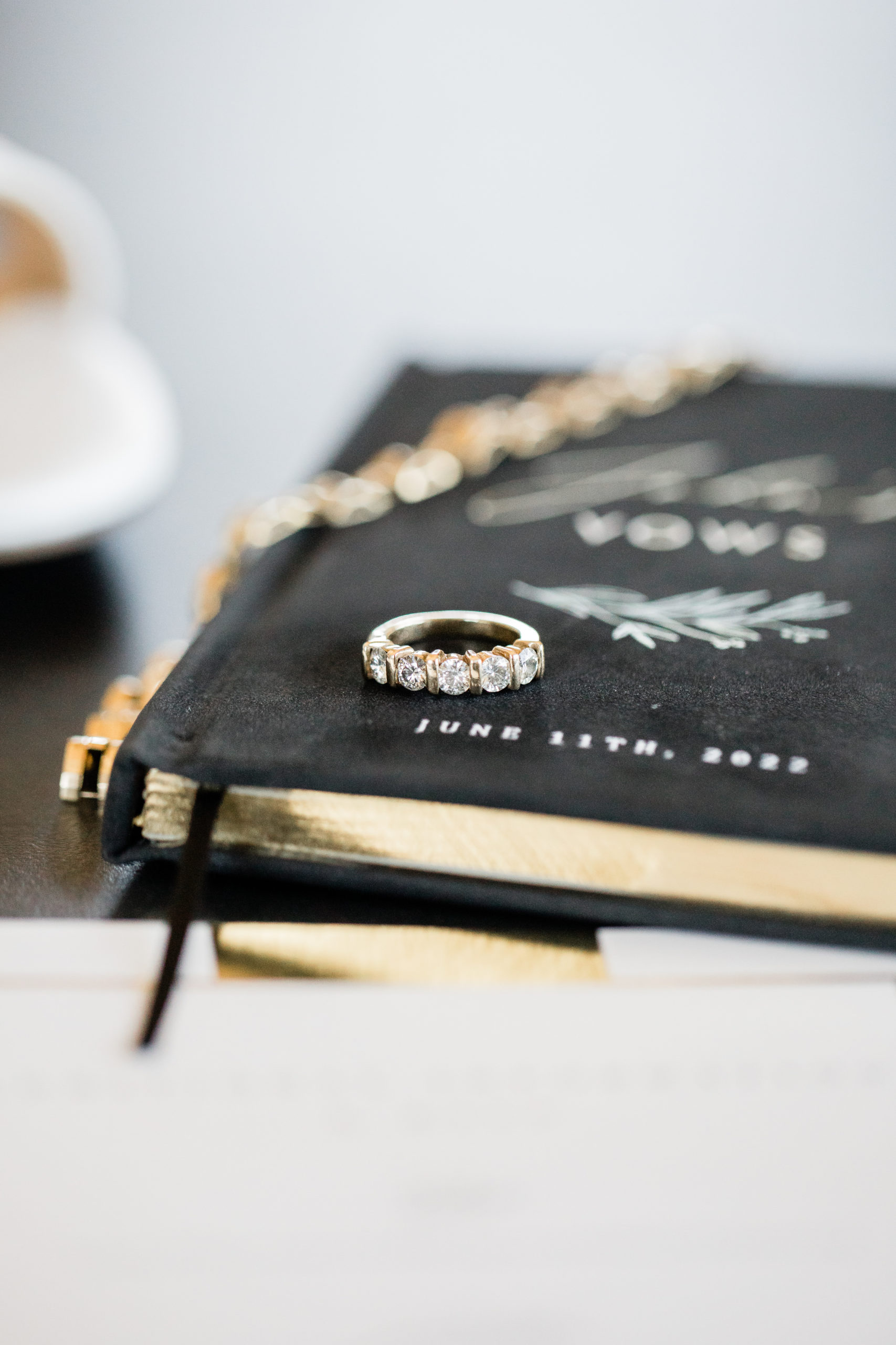 A gold bracelet and two gold rings on top of a "John's vows" book.