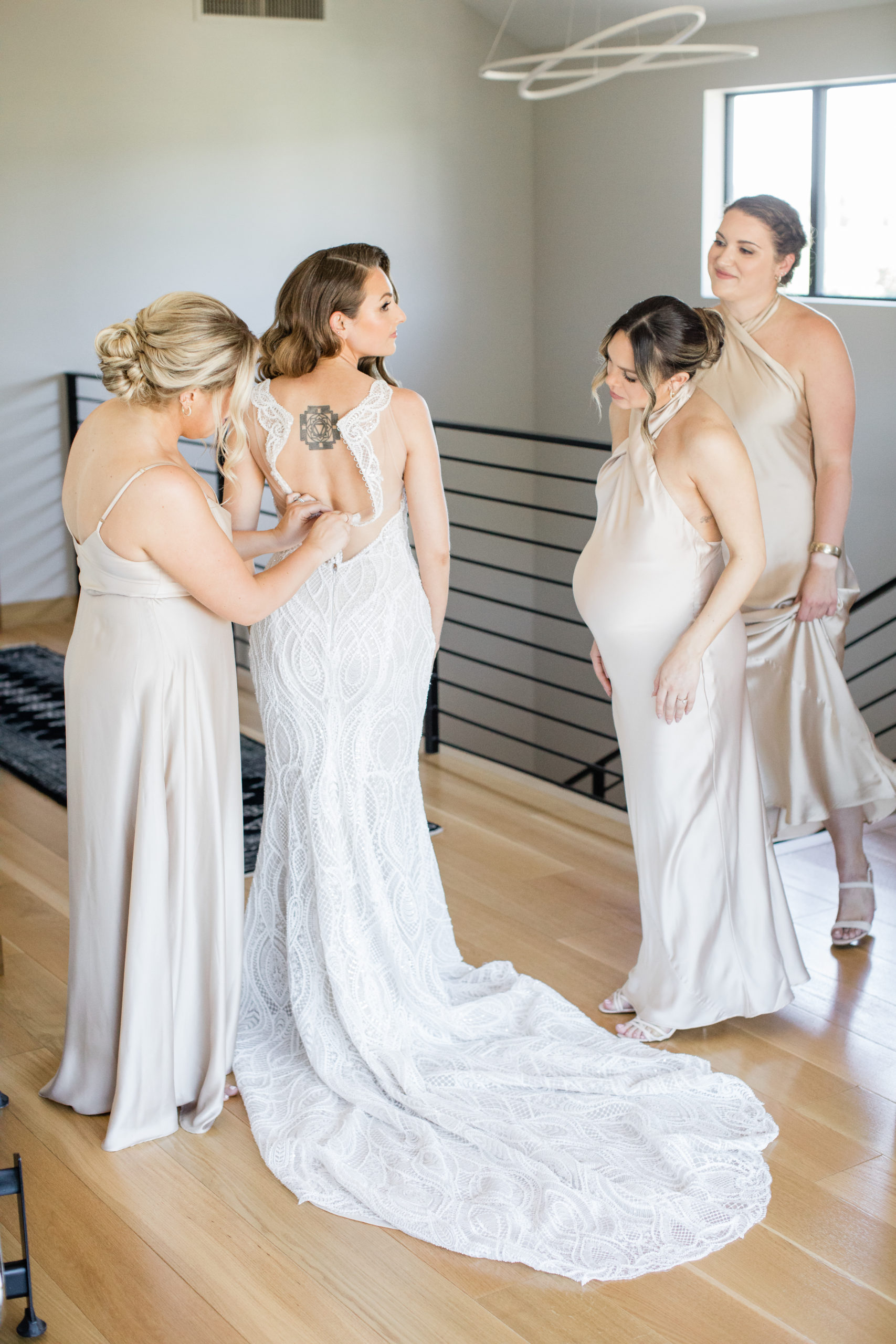 Tara's three bridesmaids helping to button up her wedding dress.