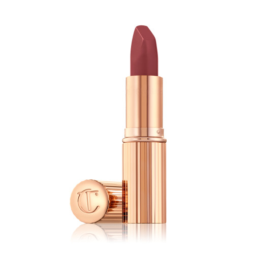 A photo of a gold lipstick tube with a berry lipstick popping out of the top