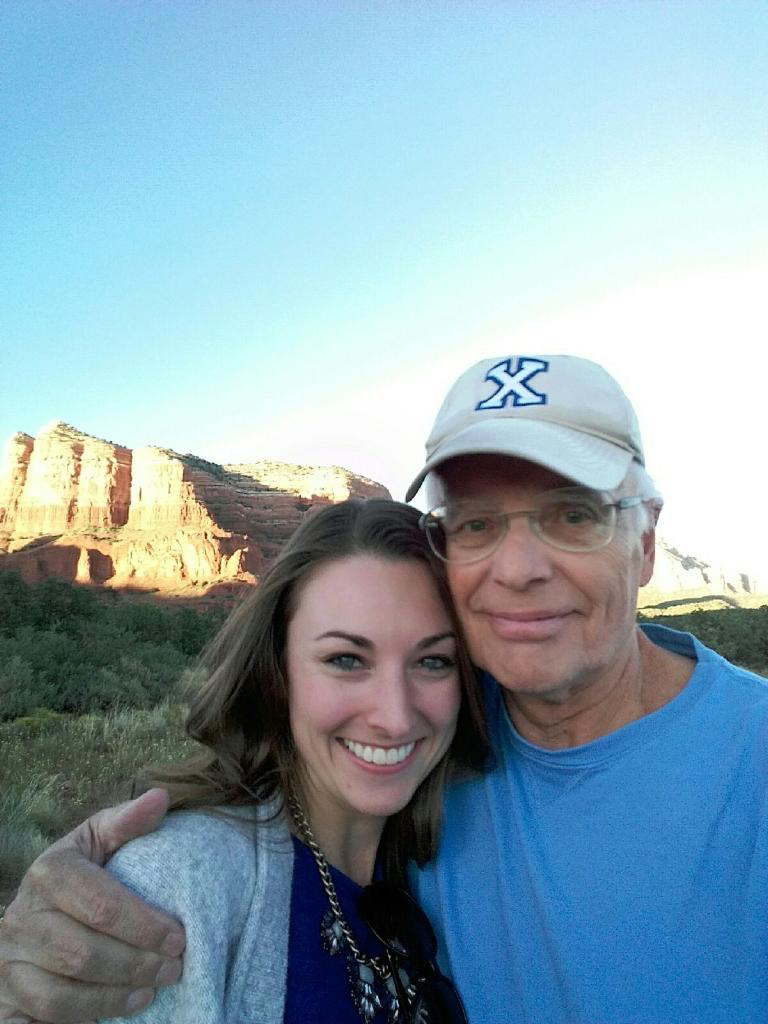 A father and daughter with his arm around her in front of a bluff in Arizona