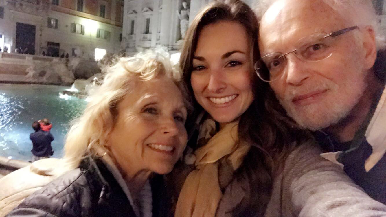 A mother, daughter, and father in front of the Trevi Fountain in Rome, Italy