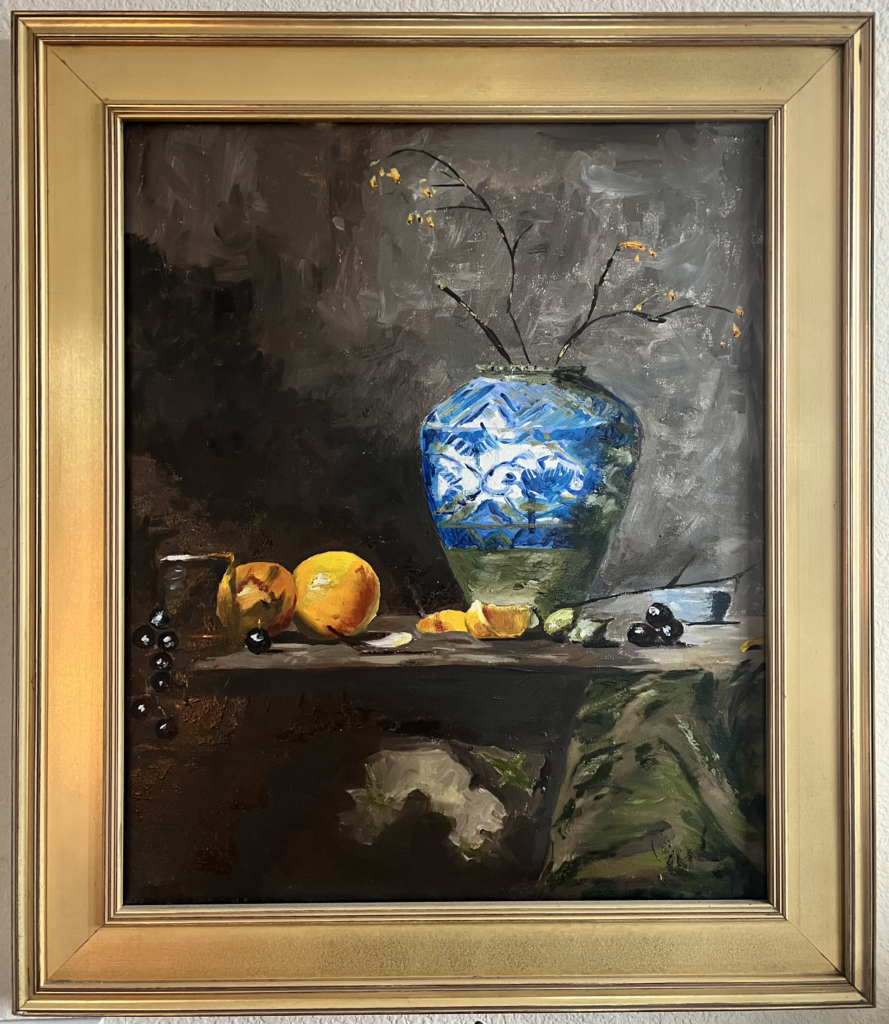 A painting in a gold frame of a white and blue vase with orange fruit to the left, sitting on a table.