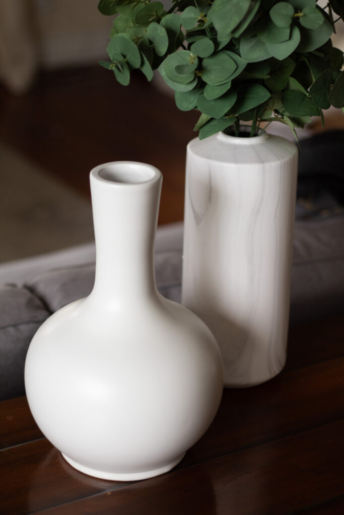 White Welkin urn with a white vase with greenery in it