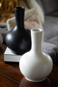 One white urn and one black urn on a dining table